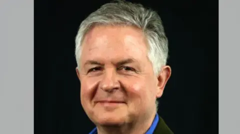 RoadPeace A head shot of a man with short grey hair smiling into the camera