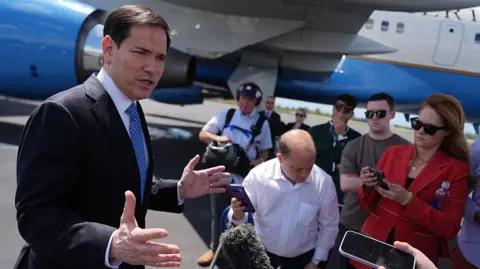 US Secretary of State Marco Rubio speaks to the press in front of a plane