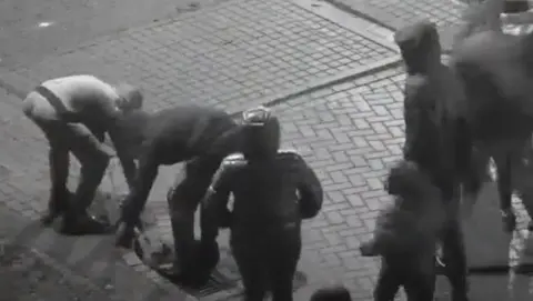 West Yorkshire Police A group of young people are seen on CCTV bending down to pick up stones