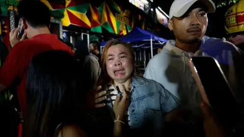 A relative of a victim in tears outside the bar in Bangkok that was hit by a fierce fire