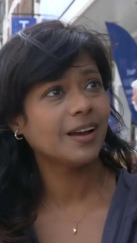 A woman is looking to the side of a camera. The wind is blowing her hair.