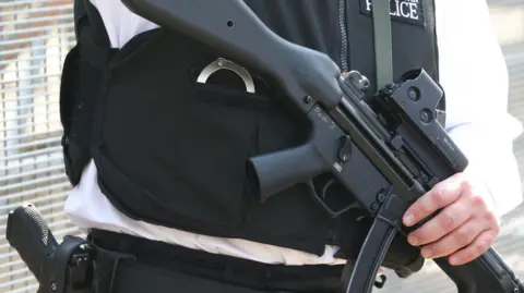 A stock image of an armed police officer holding a gun.