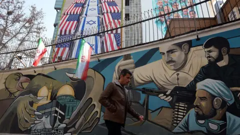 EPA An Iranian man walks near an anti-US and Israel banner hanging at the Palestine square in Tehran, Iran.