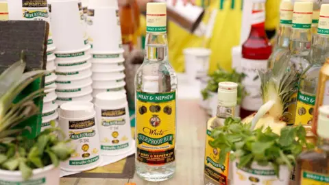 A bottle of white rum on a table with cups