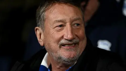 Getty Images Steven Knight pictured smiling while wearing a blue and white scarf at a Birmingham City game