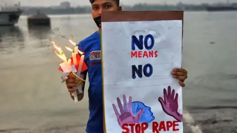 Getty Images KOLKATA, INDIA - 2019/11/30: A protester holds a placard that says Stop Rape and lighting Candles during a Protest seeking for justice and against the Gang Rape case of Priyanka Reddy. Priyanka Reddy, A Lady Veteran (26 yrs old) from Hyderabad, India was brutally Gang Raped & Burnt alive on 28th November by Four Truck driver on a Highway as per Police Information. Latest update says, a magistrate in Telangana's Shadnagar town sent all four accused to judicial custody for 14 days. (Photo by Avishek Das/SOPA Images/LightRocket via Getty Images)