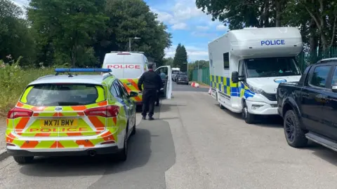 Several police cars/ vans parked on a roadside
