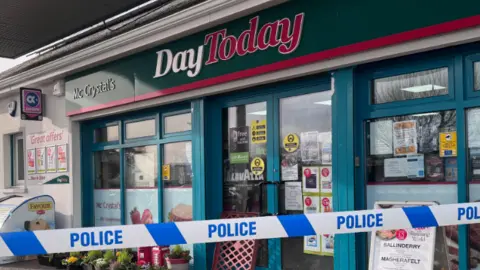 A 'Day Today' filling station with a police cordon over the front of it. 