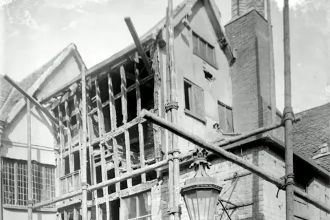 Record Office for Leicestershire, Leicester & Rutland A black and white photograph showing the exposed timbers of the building behind scaffolding in the 1920s