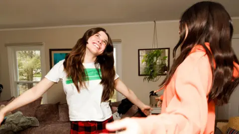 Two young women dancing at home in casual clothes