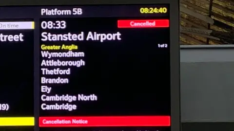 An information screen at Norwich railway station showing the 08:33 BST train as being cancelled