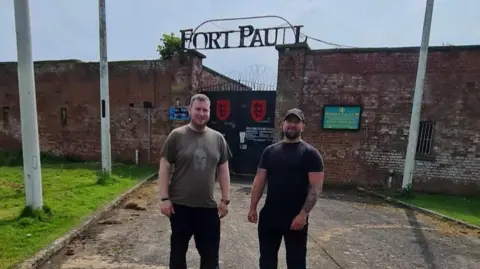 Nick Moore and Nick Taylor stand outside the visitor attraction which has a sign above the entrance that says Fort Paull.