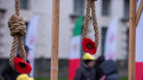 File photo: Iranian opposition supporters protest hang red flowers from nooses during a rally on the 45th anniversary of Iran's Islamic Revolution, in London, UK (10 February 2024)