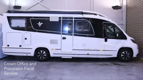 COPFS A white and blue motorhome parked in a garage 