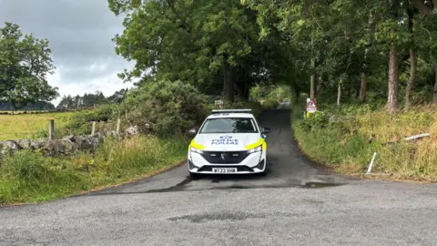 A police car parked on a wooded lane
