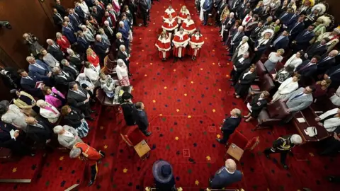 Reuters Seen from above, King Charles III and Queen Camilla in the Senate Chamber at the Senate of Canada with filled seats on the side and Supreme Court justices seated in the chamber's centre.