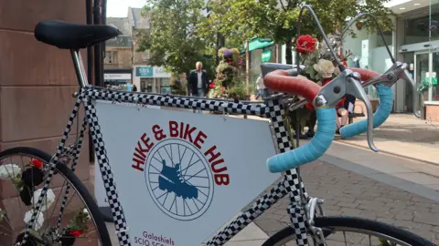 SOSE A bike patterned with checkers and flowers in a basket sits in front of a high street