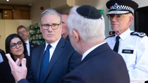PA Media Prime Minister Sir Keir Starmer (centre) Metropolitan Police Commissioner Sir Mark Rowley (right) and Home Secretary Shabana Mahmood speaking with members of the Jewish community during a visit to Golders Green, north west London on Thursday, following a terror attack on Wednesday morning in which two men were stabbed