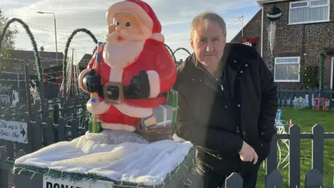 Tony Swift stood next to a Santa Claus statue 