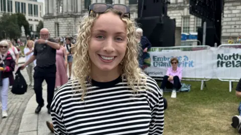 Ellen Wright, a woman with blonde hair, wearing a blue and white striped top.