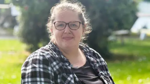 A woman in glasses and a black and white checked shirt.
