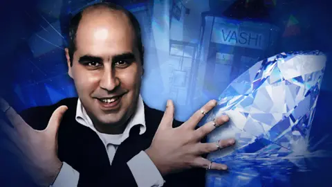 BBC A composite image with a portrait of Vashi Dominguez, a balding man with dark hair at the sides of his head, wearing a dark suit and a white shirt, smiling at the camera with his arms crossed over his body and gleaming rings on each of his fingers. The blue background of the image features sparkling diamonds overlaid on top of an image of the front of one of his Vashi retail stores.