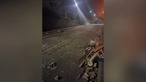 Taliesin Henty-Dodd A street covered in bricks and debris in the early hours of the morning