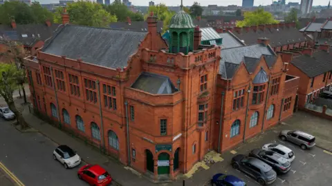 Getty Images An aerial view of Salford Lads Club, showing the red brick building, which has grey roof tiles and a green upper tower