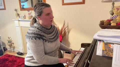 Toni Kalvans playing piano in her living room