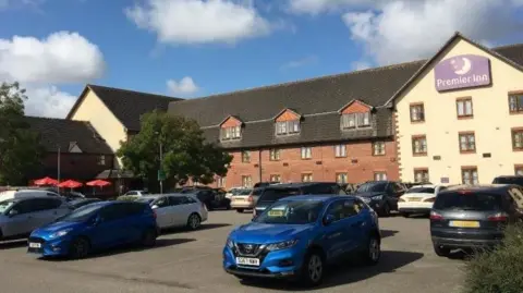 LDRS A general view of Peterborough's Premier Inn Hotel. The building is a mixture of red brick and yellow paint. Cars are parked outside in its car park.