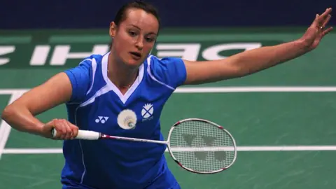 A woman playing badminton, wearing blue and white as she is representing Scotland.