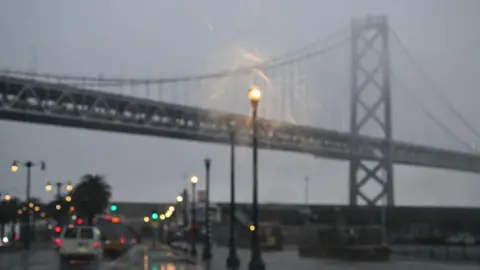 Getty Images Vehicles drive under San Francisco-Oakland Bay Bridge in rainy, grey weather in San Francisco, California, in December 27, 2023.