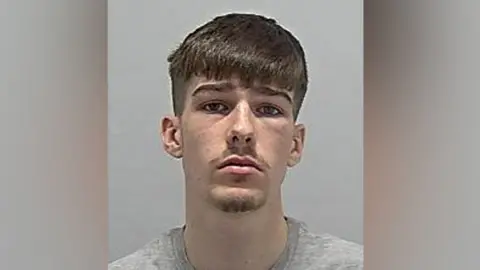 Bedfordshire Police A police mugshot of Jacob Zuco, who has brown hair that is cut just above his eyebrows. He has stubble and a serious look on his face.
