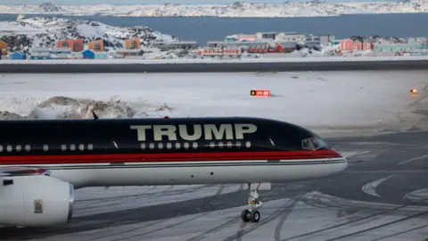 Getty Images An aircraft carrying President Donald Trump's son, Donald Trump Jr, arrives in Nuuk, Greenland on 7 January 2025. The name "TRUMP" is painted on the plane in large silver letters. Colourful buildings and snow are visible in the background