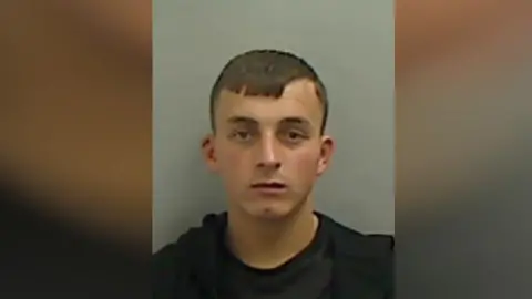 Cleveland Police A mugshot of Lennox Crockett who has brown short hair and is wearing a black jumper.