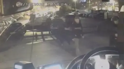 A grainy image of people walking to a bus 