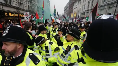 PA Media Police officers watch as people take part in a pro-Palestinian march  on Whitehall in central London