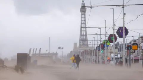 Reuters People run through wind and rain in front of The Blackpool Tower