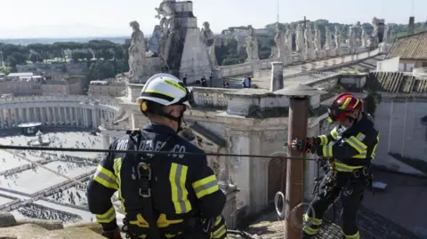 EPA Images show firefighters installing the chimney atop the Sistine Chapel in Vatican City on 2 May 2025