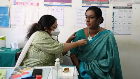 Getty Images A doctor (L) examines a transgender woman at a free clinic for members of the transgender community in Hyderabad on January 28, 2023. (Photo by NOAH SEELAM / AFP) (Photo by NOAH SEELAM/AFP via Getty Images)