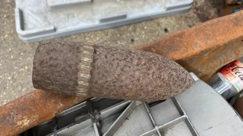 A large bullet-shaped piece of rusty metal with a ridge around its wide end