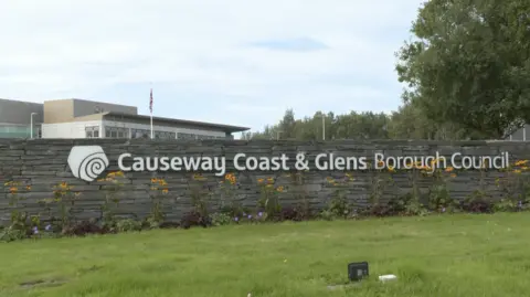 BBC The stone wall outside Causeway coast and Glens council with the logo and words on it in metal.