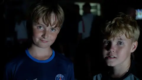Jamie Niblock/BBC Taylor and Stanley are smiling after the game. They are both 11 years old. Taylor is wearing a navy PSG top and Stanley a light grey one.