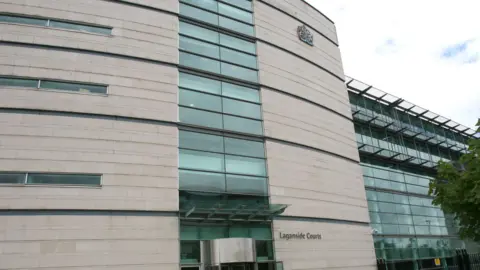 PA Media Laganside courthouse in Belfast with white brick walls and glass panels. The sky is cloudy and grey