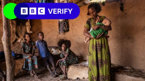 A mother holds her baby in a room with her family in Tigray