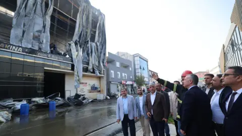 Kocaeli Metropolitan Municipality Mayor of Kocaeli Metropolitan Municipality Tahir Buyukakın is shown the fire ravaged building by a firefighter 