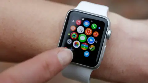 Close up of an Apple Watch with a white strap on a person's wrist, with their index finger tapping the screen