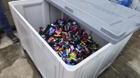 Hayley Coyle/BBC A plastic container full of brightly coloured vapes 
