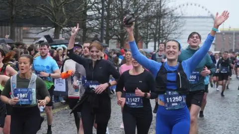 Some women raise their hands in triumph as they cross the finish line.
