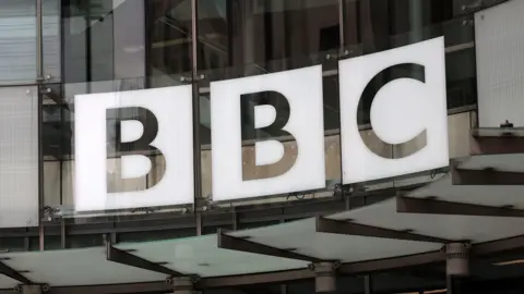 File image showing the BBC logo above the entrance to New Broadcasting House, consisting of a white silhouetted logo on curved glass